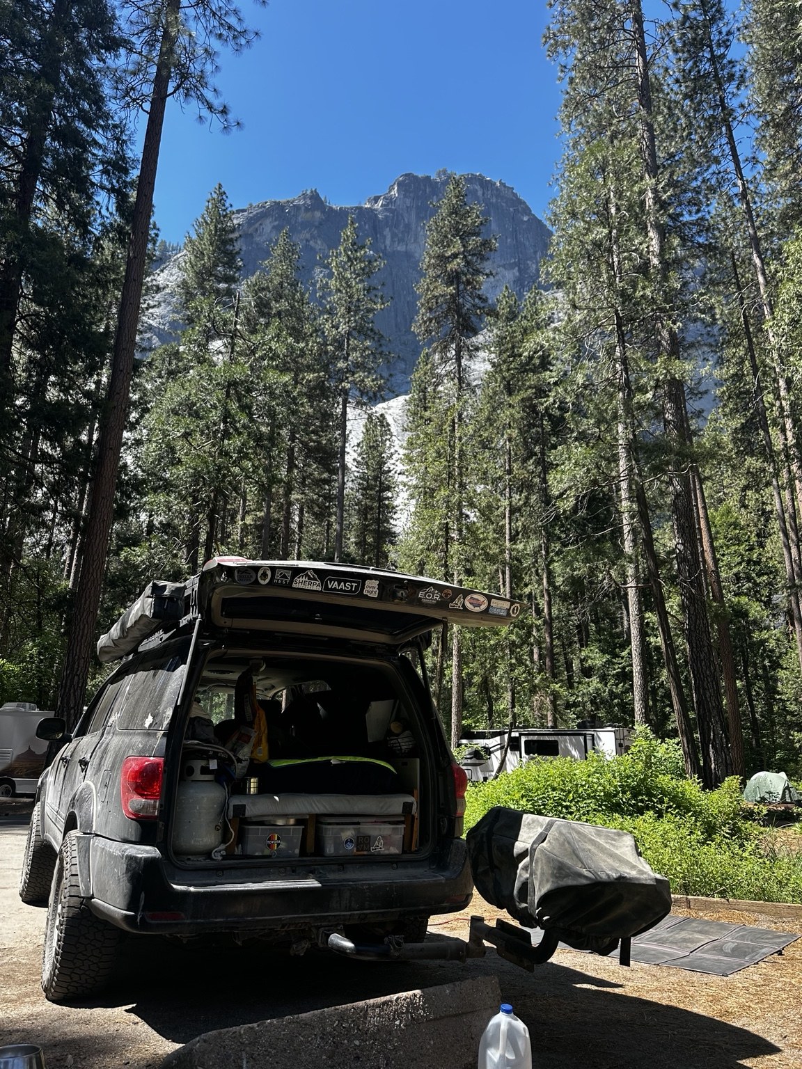 Open rear of the Sequoia, revealing the sleeping area at a forest campsite.